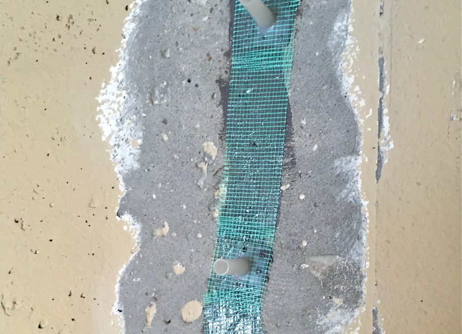 Fiberglass tape over an in-progress wall crack repair