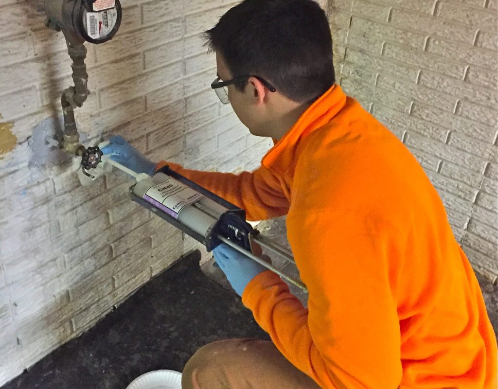 A Sealed LLC technician completing the final filling steps of a leak repair