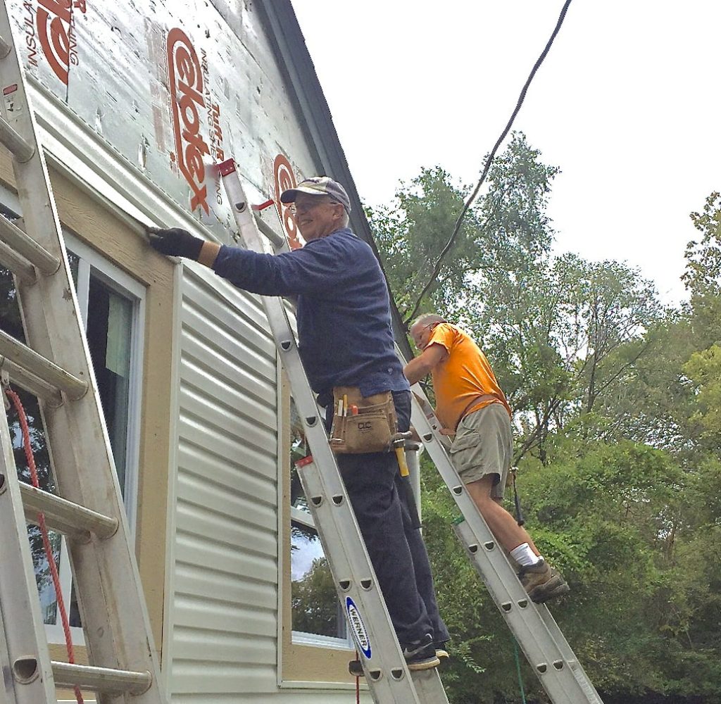 A group of volunteers working on the siding at the Fuller House